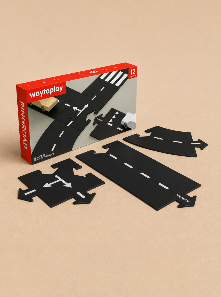 A box labeled “WaytoPlay: Small Flexible Toy Road Set - Ringroad” is displayed, with four black, flexible road toy pieces featuring white markings arranged in front on a light brown surface—perfect for imaginative play.