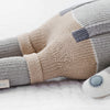 The Cuddle + Kind Noah the Dog, a fair trade hand-knit doll, rests on a white surface, displaying thoughtful craftsmanship and ethical sourcing.