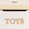 The Toy Storage Box features a white wooden design with large, embossed "TOYS" letters on the front and a slightly open lid. Ideal as kids’ storage or stylish toy storage furniture. "Embossed Lettering" displayed above.