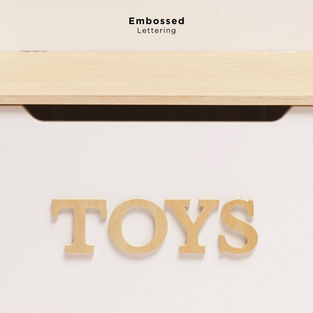 The Toy Storage Box features a white wooden design with large, embossed "TOYS" letters on the front and a slightly open lid. Ideal as kids’ storage or stylish toy storage furniture. "Embossed Lettering" displayed above.