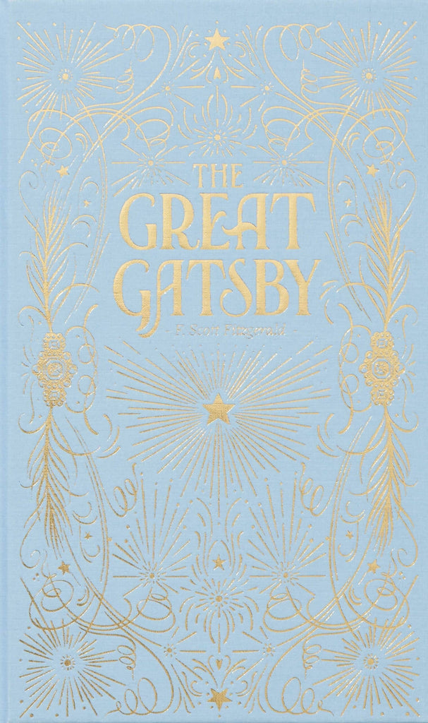 A luxe hardcover edition of "The Great Gatsby" by F. Scott Fitzgerald, featuring a light blue cover with ornate gold patterns and stars, plus the title and author's name in large, elegant gold lettering at the center.