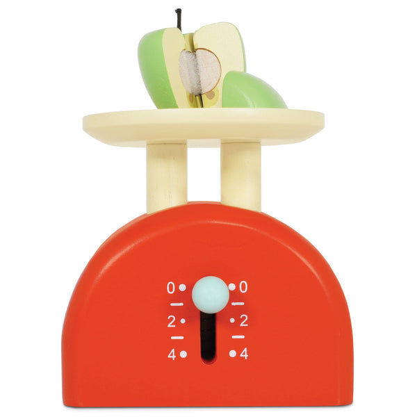 The Kitchen Weighing Scales is a wooden pretend play toy with a red base, cream top, and sliding dial from 0 to 4. Includes a green and white apple cut in half—perfect for kitchen role play fun.