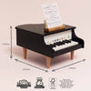 The Wooden Grand Piano Toy is a small black piano with wooden legs, labeled keys, and sheet music on a stand. Measuring 242mm high, 425mm wide, and 340mm deep, it’s made from sustainable FSC-certified wood to inspire early musical skills.