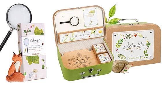 The Moulin Roty Botanist Suitcase is a children’s nature observation kit with a magnifying glass, illustrated fox and hedgehog, “Le botaniste” and “La loupe” boxes, botanical designs, flower press, all packed in a charming suitcase for young explorers.
