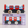 A wooden toy train with a red, white, and blue design sits on top of a purple box labeled “No. 48 GT290 Tim | Made in England.” Perfect for imaginative play inspired by metro transport adventures, the box also features an illustration matching the train.