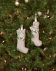 The Coral & Tusk Puppy Stocking Ornament decorates your tree with festive charm, featuring a red-striped stocking, holly embroidery, and an adorable puppy peeking out.
