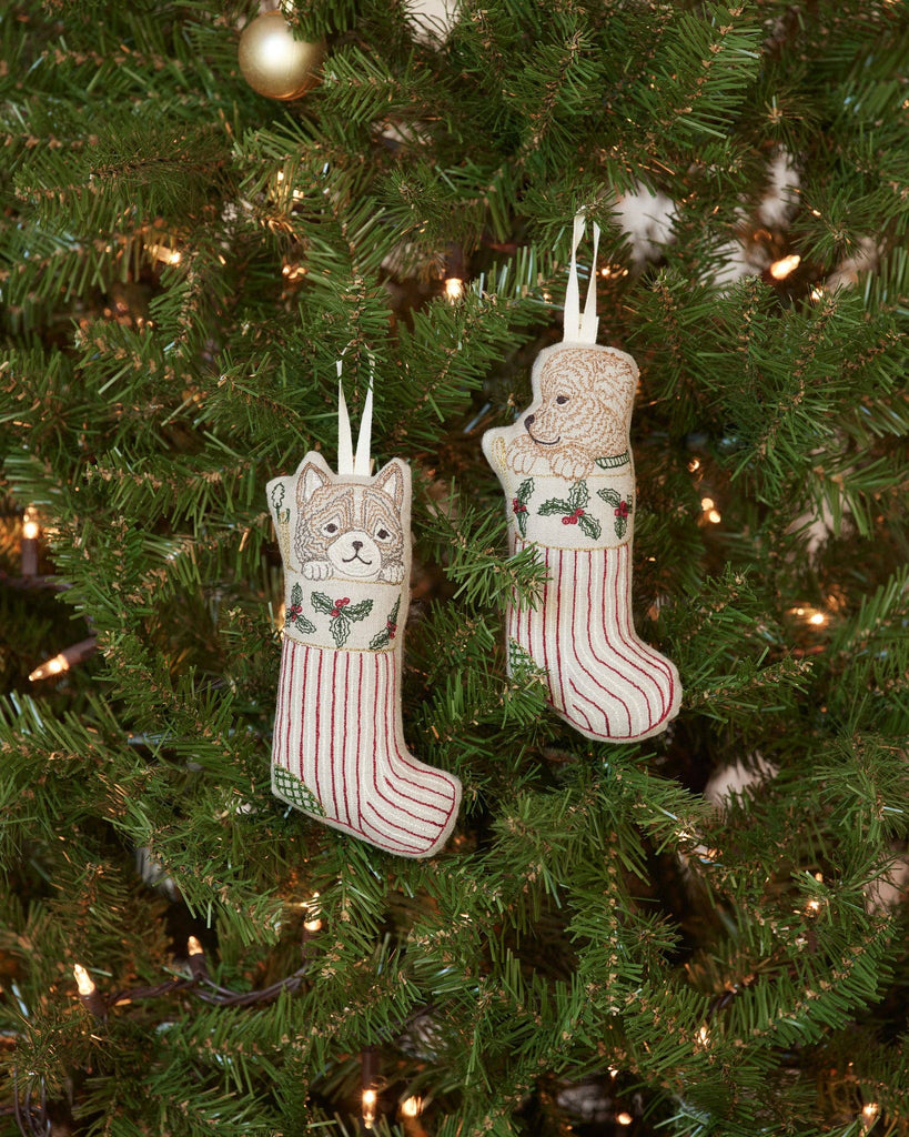The Coral & Tusk Puppy Stocking Ornament decorates your tree with festive charm, featuring a red-striped stocking, holly embroidery, and an adorable puppy peeking out.