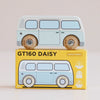 A vintage wooden campervan in light blue rests on a yellow box labeled “No. 29 GT160 Daisy | Made in England,” featuring an illustration that matches the charming retro toy. The packaging displays icons and text indicating it is a limited edition and suitable for ages 2 and up, making it ideal for nostalgic play.