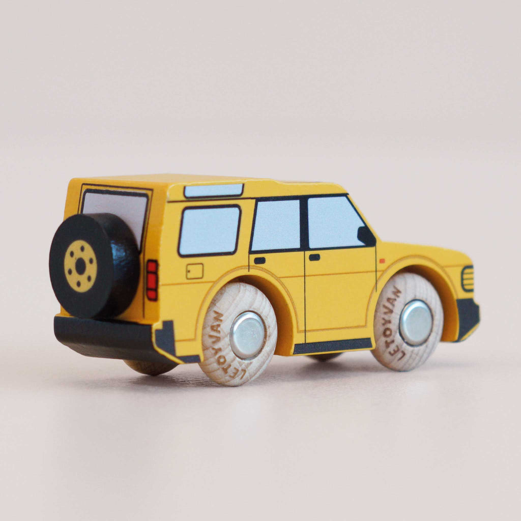The No. 35 GT195 Riley | Made in England is a yellow wooden toy SUV featuring black and white details, four sturdy wooden wheels, and a black spare tire mounted on the back. Photographed against a light background, it’s perfect for imaginative play and inspired by classic off-road vehicles.