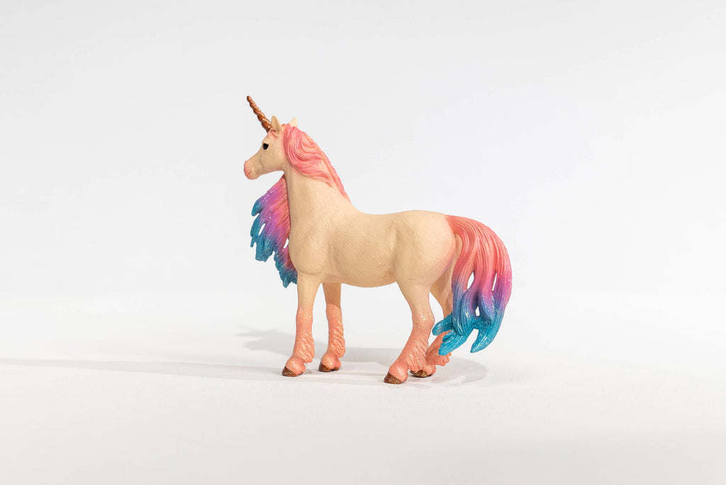 The Schleich Marshmallow Mare Unicorn, a limited edition figure featuring a pink body, gold horn, and a mane and tail that fade from pink to blue, stands on a white background.