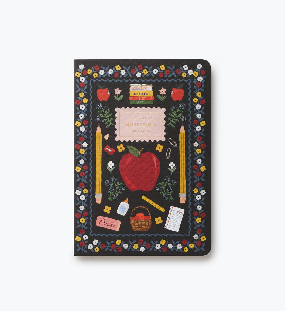 The Assorted Set of 3 Schoolhouse Notebooks features stitched binding and black covers adorned with a charming red apple, flowers, pencils, an eraser, notebook, basket, and vibrant small illustrations—all encircled by a lovely floral border. Perfect as school notebooks, these are thoughtfully designed with convenient lay-flat binding.
