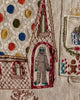 A close-up of the Coral & Tusk North Pole Advent Calendar shows colorful embroidery, including a small white figure with blue hands and feet in a pointed archway, alongside stitched polka dots, windows, gifts, gingerbread men, and other festive motifs.
