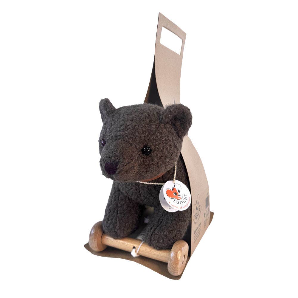Pull-Along Raoul is a crocheted brown bear plush toy that sits on small wooden wheels and comes packaged in a cardboard holder with a handle and a round tag hanging from its neck.