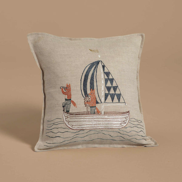 The Coral & Tusk Sailing Foxes Pillow is a delightful piece of decor showcasing an embroidered design of two foxes on a sailboat. One fox uses a telescope while the other sits, and the boat's sail highlights geometric patterns on a beige background.