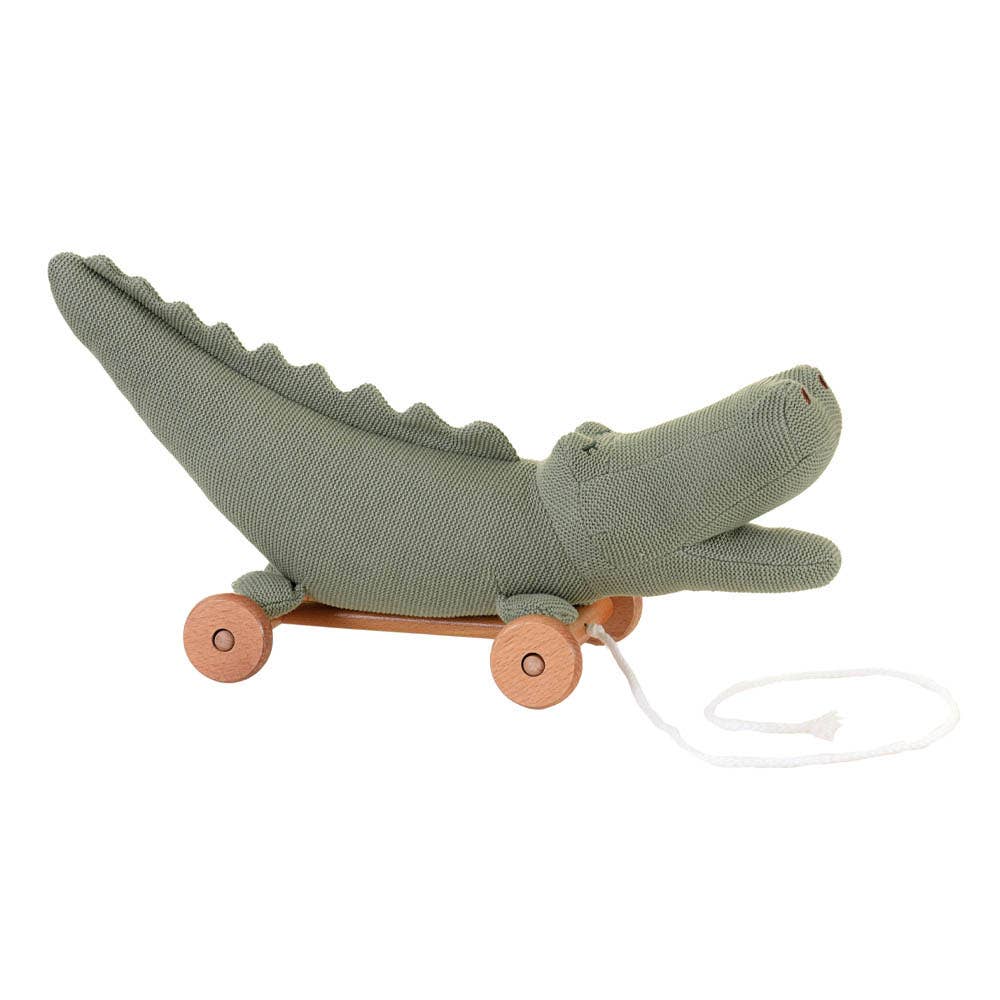The Pull-Along Croc by Egmont Toys is a green knitted crocodile on a wooden wheeled base with a white pull string, designed to delight little ones and encourage the development of gross motor skills.