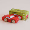 A small red wooden No. 25 GT140 Marco racing car with black details sits in front of a green box labeled “GT140 MARCO Limited Edition | Made in England.” The box features illustrations and logos that evoke the spirit of a classic racing car, while the background is a plain light surface.