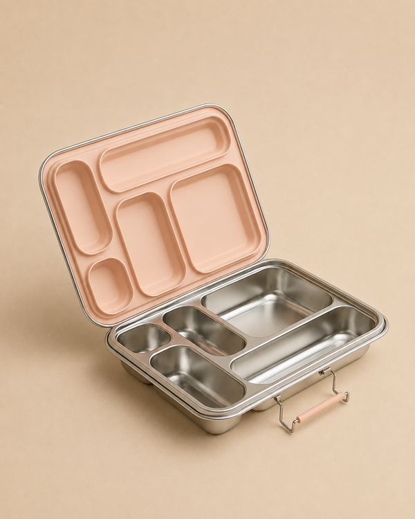 The Haps Nordic - Stainless Steel Lunch Box - Multi-Compartment (Blush) sits open on a beige surface, showcasing its matching blush-colored lid with convenient section dividers.