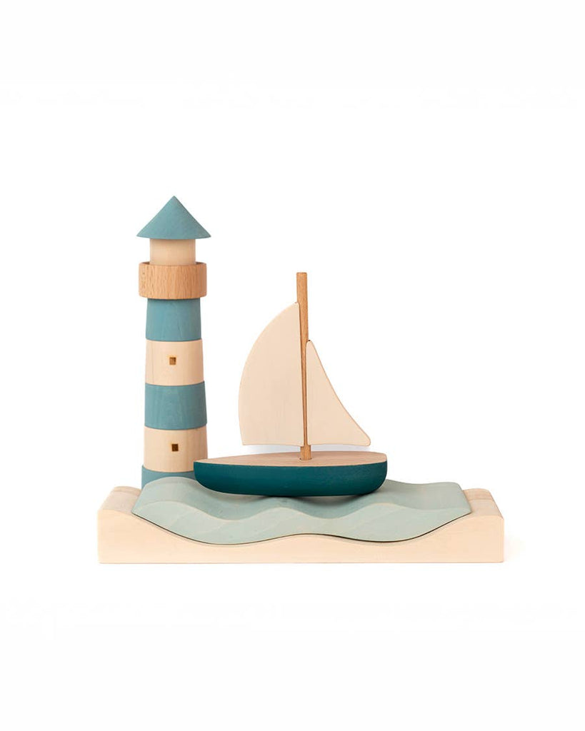 Sabo Concept Sea Adventure Set features a wooden lighthouse and sailboat on a wavy base in blue, teal, and natural wood—perfect for imaginative ocean play against a plain white background.
