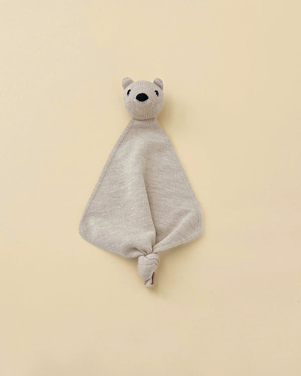 A beige small merino wool lovey with a head of a teddy bear at top.