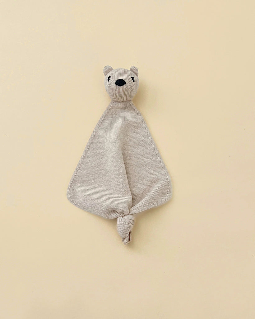 A beige small merino wool lovey with a head of a teddy bear at top.