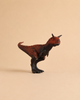 A Schleich Carnotaurus Large Realistic Dinosaur Toy With Movable Jaw, featuring striking red and black coloring, stands on two legs against a plain beige background. This educational toy captures the fierce look of the prehistoric predator.