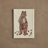The Coral & Tusk Mama Bear and Cub Card features a stitched bear holding a cub’s paw, surrounded by embroidered flowers on light fabric—a charming design perfect for a keepsake or baby shower card.