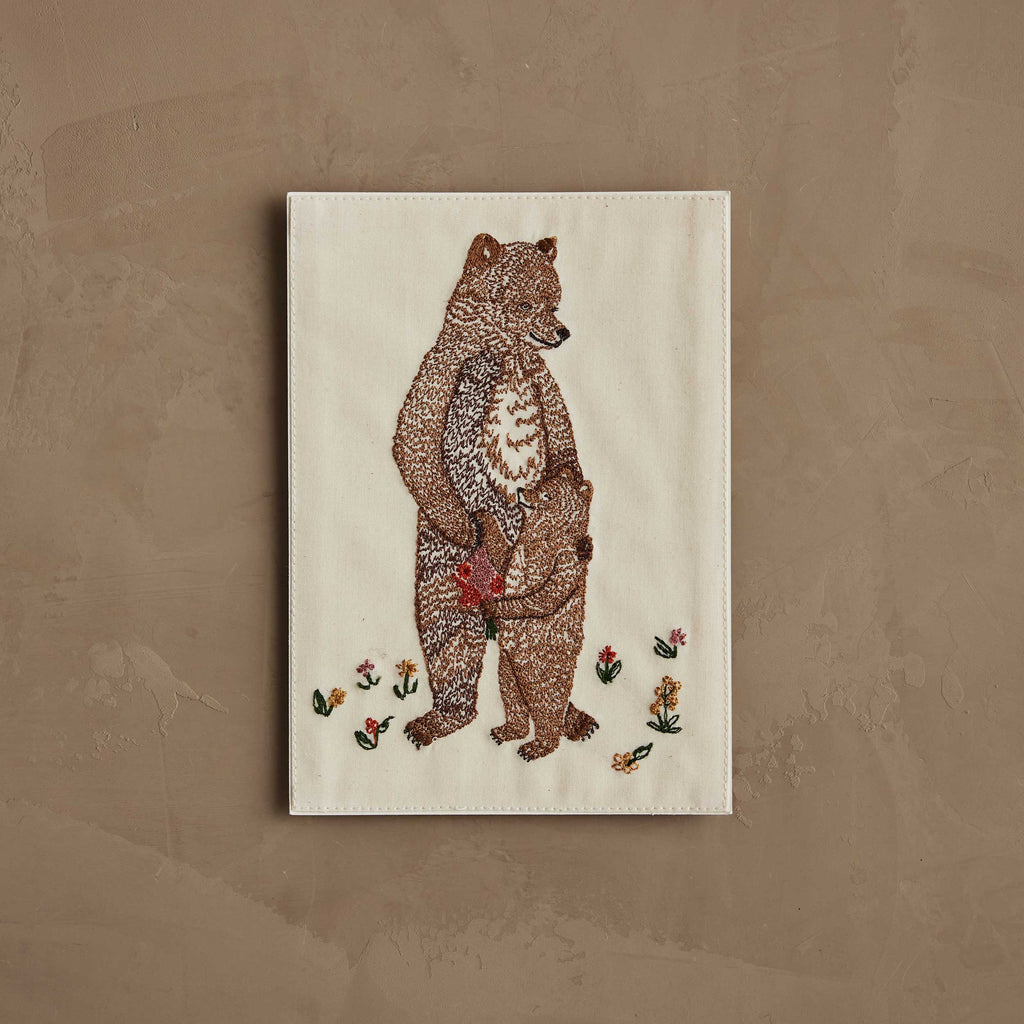 The Coral & Tusk Mama Bear and Cub Card features a stitched bear holding a cub’s paw, surrounded by embroidered flowers on light fabric—a charming design perfect for a keepsake or baby shower card.