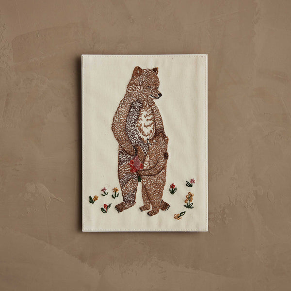 The Coral & Tusk Mama Bear and Cub Card features a stitched bear holding a cub’s paw, surrounded by embroidered flowers on light fabric—a charming design perfect for a keepsake or baby shower card.