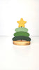 The Handmade Wooden Stacking Toy Green Christmas Tree features three green layers, a yellow star topper, and "Atticus" engraved on the wooden base—an eco-friendly holiday toy.