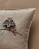 The Coral & Tusk Bat Branch Pillow features beige bat wings, an embroidered tree branch with baby bats, and a 3D bat brooch. Set against a neutral wall, it's perfect for Halloween décor. Ships in one week.