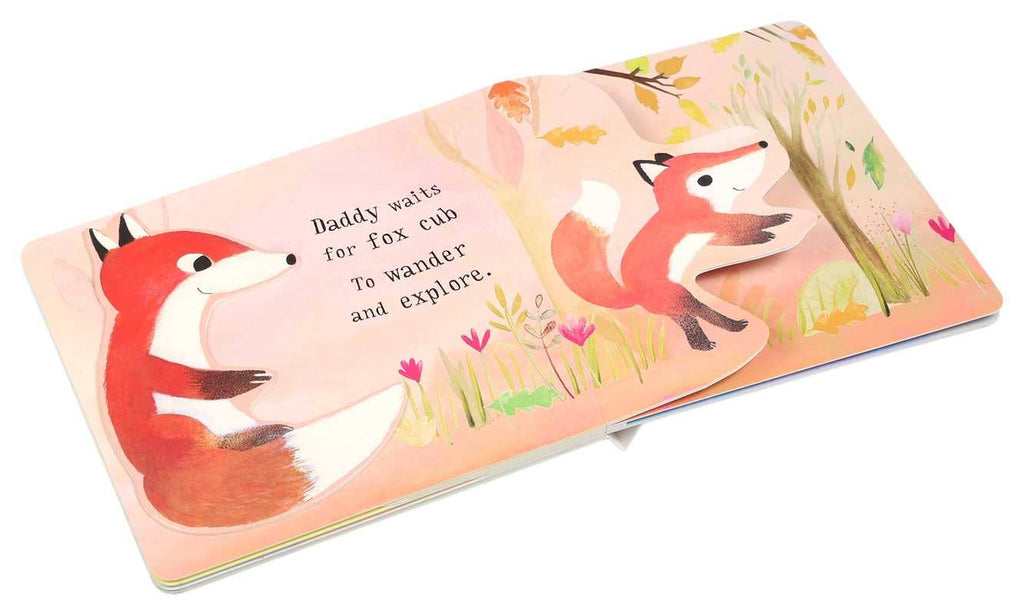 A page from "I Love You So" by Patricia Hegarty shows two baby foxes in a vibrant forest. The text says, "Daddy waits for fox cub to wander and explore." One fox is partially cut out in this interactive board book.