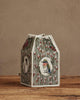 The Coral & Tusk Birdhouse Tissue Box Cover, featuring embroidered birds and floral designs, is displayed on a wooden surface against a beige wall.