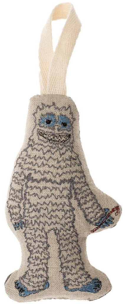 Introducing the Yeti with Candy Cane Ornament: a delightful plush decoration crafted from knitted fabric. It showcases a cheerful face, blue hands and feet, and holds a small candy cane, complete with a loop at the top for effortless hanging.