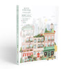 The Paint By Number Kit - New York features a city scene with vibrant buildings, shops, a bakery, greenery, and a yellow taxi. The mostly white “Petit Pinceau” box includes pastel accents—perfect for creating your next masterpiece.
