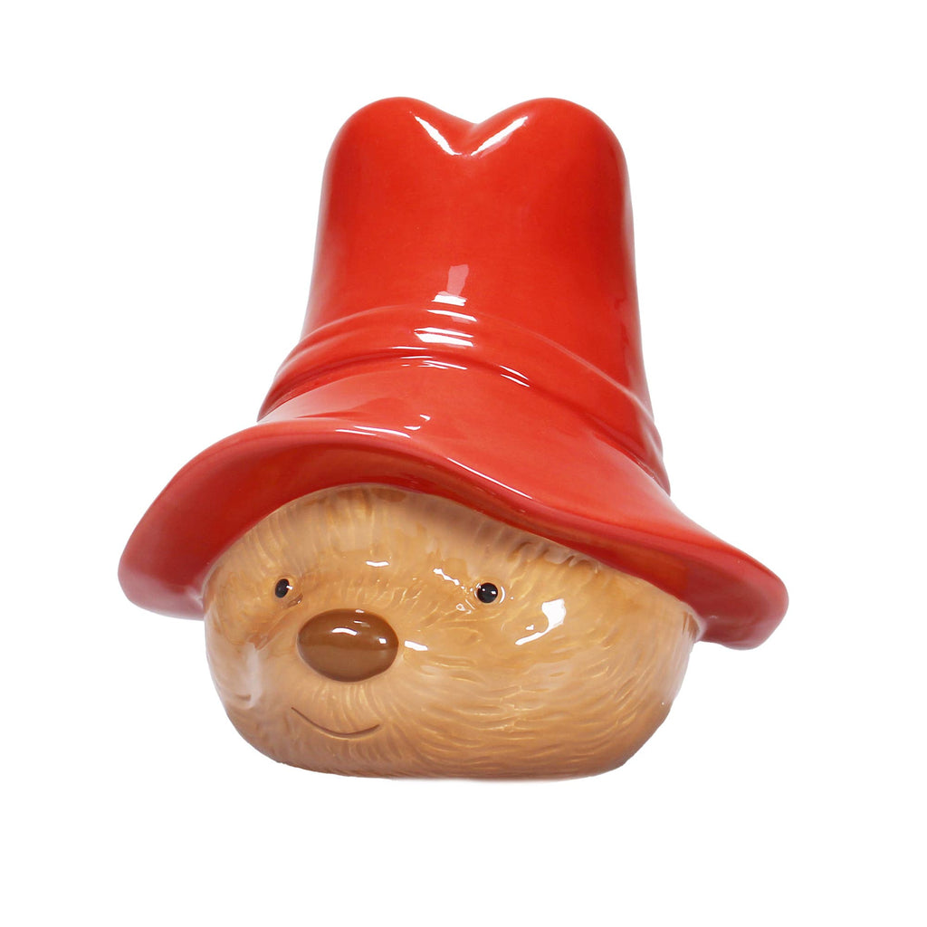 The Paddington Money Bank is a ceramic bear head coin bank with light brown fur, a big shiny red hat, a small nose, simple eyes, and a gentle smile—capturing the cute charm of Paddington Bear.