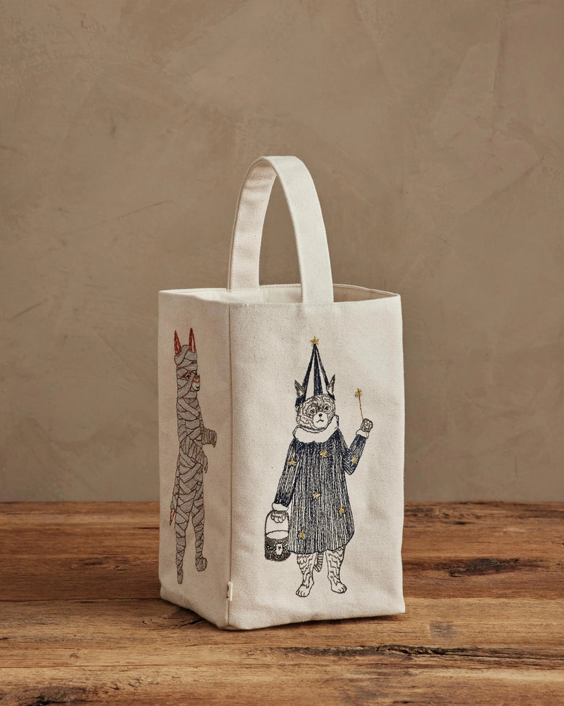 The Coral & Tusk Halloween Trick Or Treat Bag features embroidered critters—a cat mummy with red horns on one side and a bear wizard with a wand on the front. This playful fabric tote is perfect for trick-or-treating! Ships in one week.