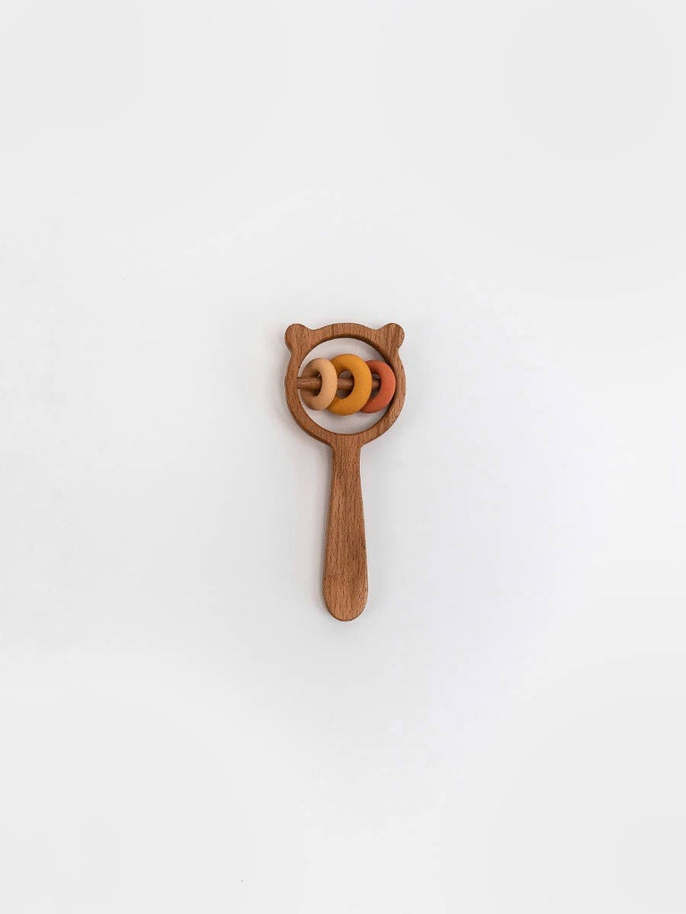 The Sabo Concept Bear and Rings Rattle in yellow and pink is a wooden rattle with a bear-shaped top, round handle, and three circular rings—perfect for boosting motor skills development on a plain white background.