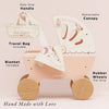 A Retro Wooden Doll Stroller in pink with a retractable canopy, wooden wheels, travel bag, and blanket, featuring labels that point to the details of this traditional doll pram.