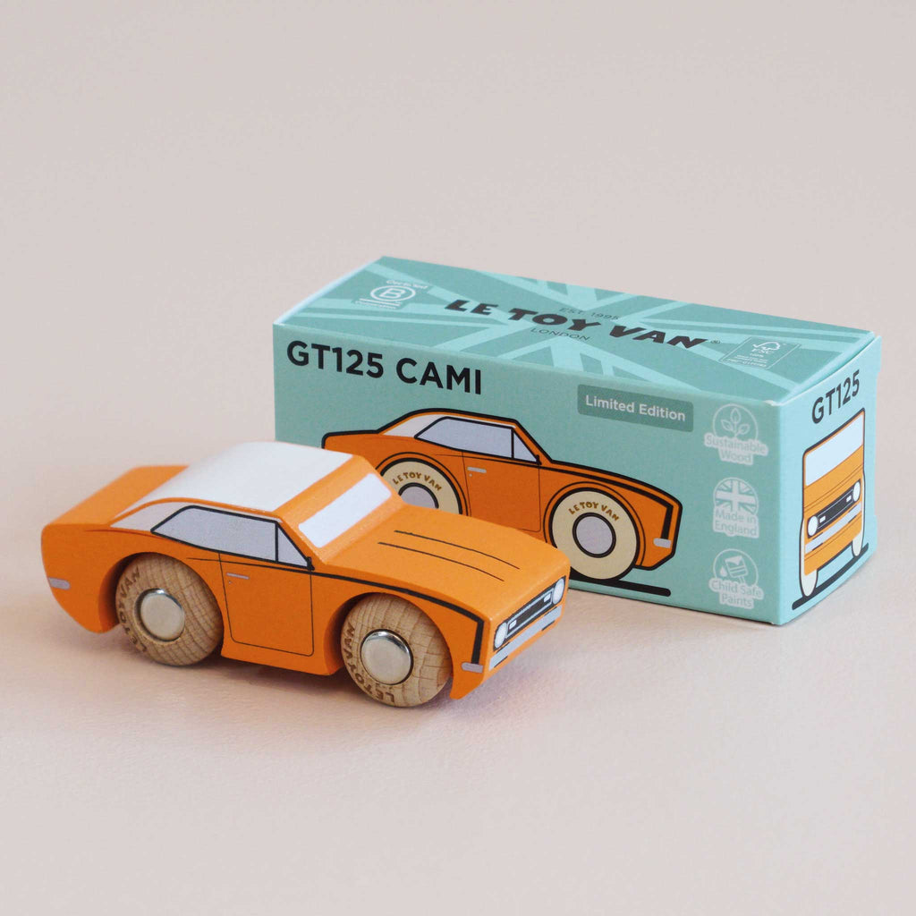 A small orange wooden racing car, the No. 22 GT125 Cami made in England, sits beside a matching box labeled “GT125 CAMI Limited Edition.” Both are adorned with illustrations and light blue accents that evoke the spirit of classic American muscle, displayed on a beige surface.