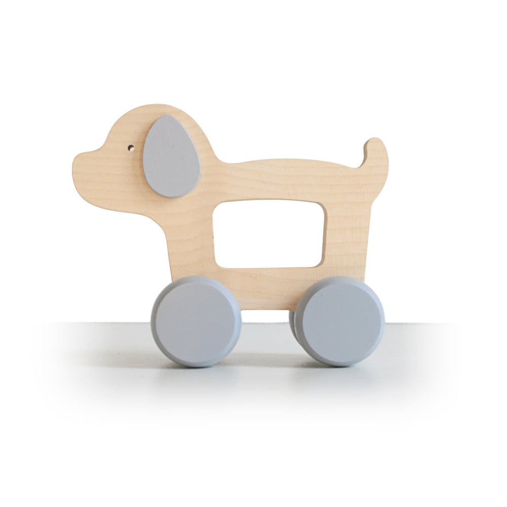 Handmade Wooden Puppy Push Toy with light blue wheels and an open center. The toy boasts a simple, minimalist design, featuring a light wood finish and flat profile. Perfect for young children to push around, it aids fine motor skills development while the ears are painted light blue.