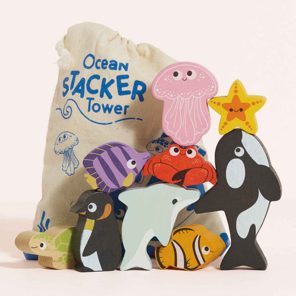 The Ocean Life Stacking Animals & Bag features colorful wooden ocean creatures like a whale, dolphin, and penguin. Perfect for sensory play—stack the charming blocks in front of the included cloth bag labeled "Ocean Stacker Tower.