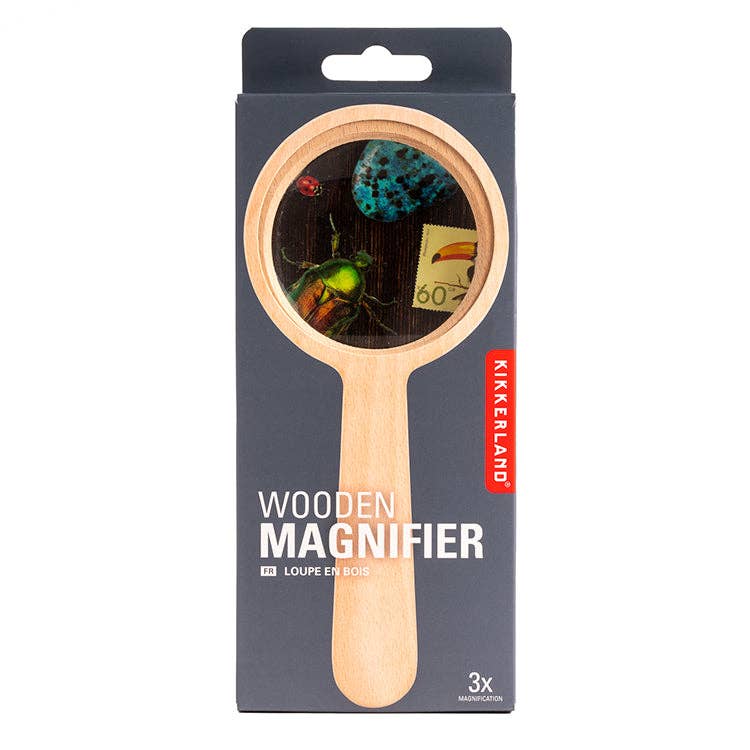 A box of Wood Magnifier with a beechwood frame and wooden handle is shown. Beetle, butterfly, and stamp images are magnified 3x through the lens, as stated on the packaging.