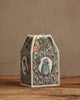 The Coral & Tusk Birdhouse Tissue Box Cover features embroidered birds and butterflies on fabric, displayed on a wooden surface against a beige wall.
