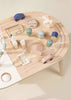 Overhead view of a small, Wooden Activity Table with assorted wooden toys including blocks, cars, and a bead maze on a beige background.
