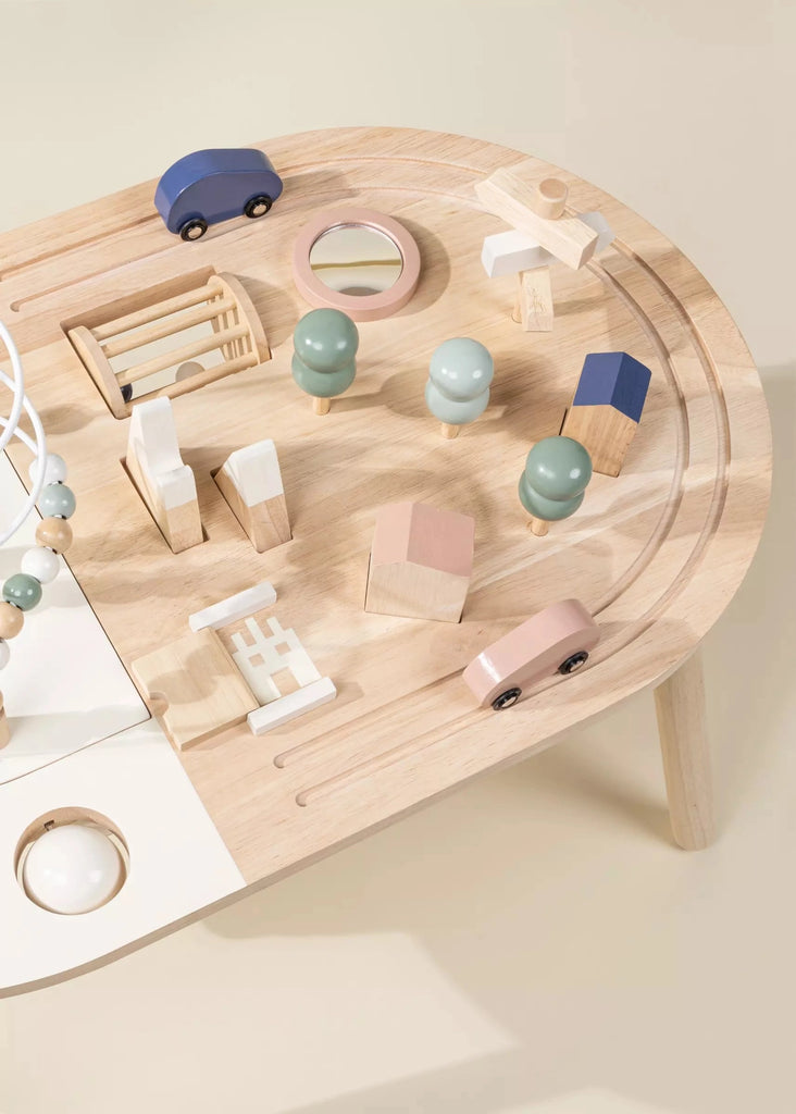 Overhead view of a small, Wooden Activity Table with assorted wooden toys including blocks, cars, and a bead maze on a beige background.