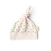 The Organic Baby Hat – Little Peach is a soft, cream-colored newborn hat made from organic cotton, featuring a knotted top, small peach patterns, and a side tag that reads "Oolie.