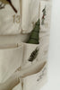 A close-up of the Sabo Concept Christmas Cotton Advent Calendar, featuring beige cotton with numbered pockets. One pocket contains a small green tree, and some pockets are accented with embroidered branches.