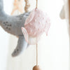 The Nautical Dreams Mobile features a soft, pink, polka-dotted fish plush with mesh fins hanging from a string, adding charming nautical style to your nursery decor.