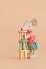 A stuffed mouse stands upright, stacking Maileg Stool Set, Mouse - Mint/Light Yellow stools with a vintage paint finish against a peach-colored background.