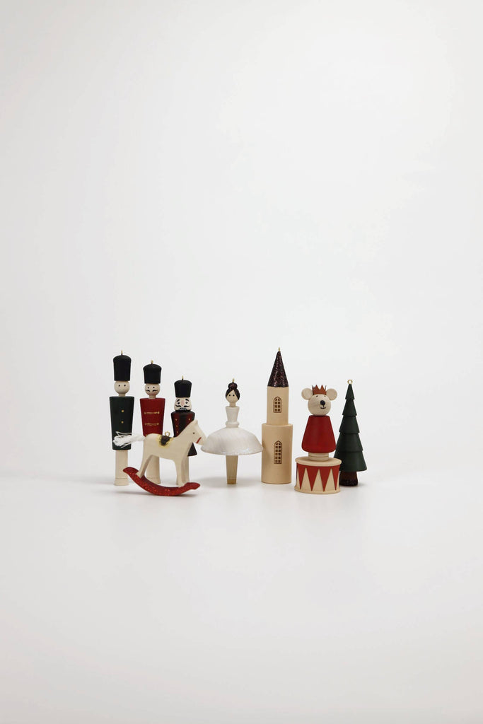 Sabo Concept Christmas Ornaments are hand-painted wooden decorations, including toy soldiers, a ballerina tree ornament, a horse, a church, a crowned bear, and a festive tree displayed on a white background.